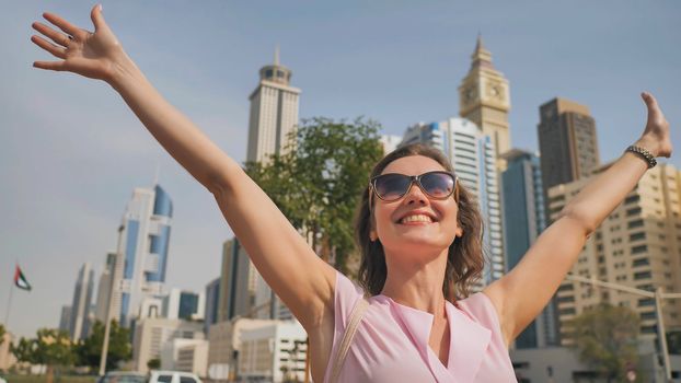 Happy girl walks in the center of Dubai against the background of skyscrapers