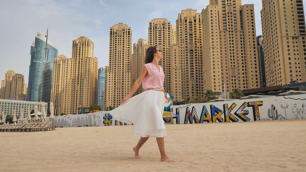 Happy girl walks in the center of Dubai against the background of skyscrapers