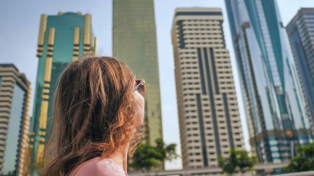 Happy girl walks in the center of Dubai against the background of skyscrapers