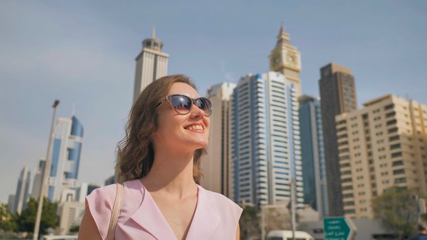 Happy girl walks in the center of Dubai against the background of skyscrapers