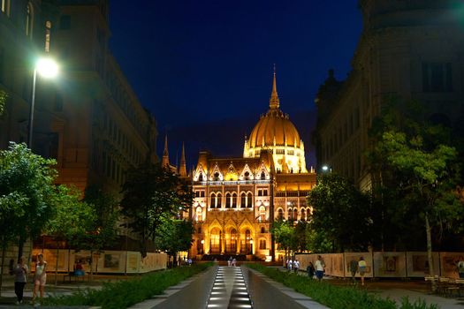 Evening photo of the Parliament building in Budapest.The majestic Saxon architecture is illuminated with warm yellow light. Budapest, Hungary - 08.24.2022