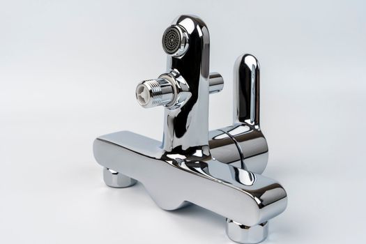 new shiny bath faucet on a white background. Bath mixer before installation. mounting nuts for mounting. Plumbing, renovation. close-up