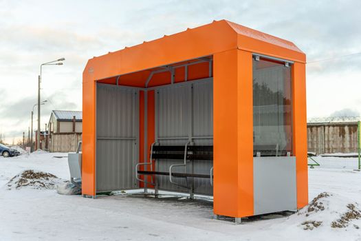 an empty orange bus stop in winter. Small empty bus stop in a cold winter day.