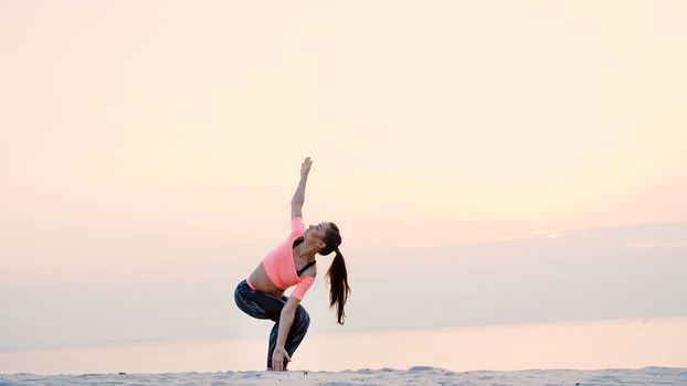 Healthy, young beautiful woman meditating, practicing yoga on the sea beach, at sunrise, Makes exercises for balance and coordination, deep muscle tone. High quality photo