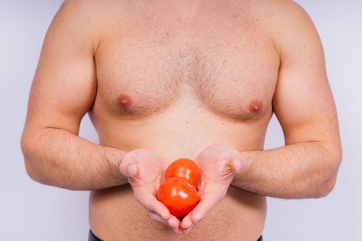 Full isolated studio picture from a young naked man with underwear and tomatoes