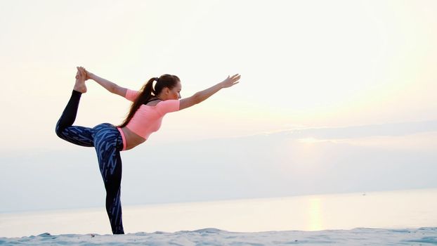 Healthy, young beautiful woman meditating, practicing yoga on the sea beach, at sunrise, Makes exercises for balance and coordination, deep muscle tone. close up. High quality photo