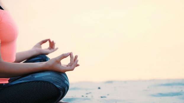 Healthy, young beautiful woman meditating, practicing yoga on the beach, by the sea, at sunrise, Relaxes muscles, mind, acquires the harmony of soul and body. close up. High quality photo