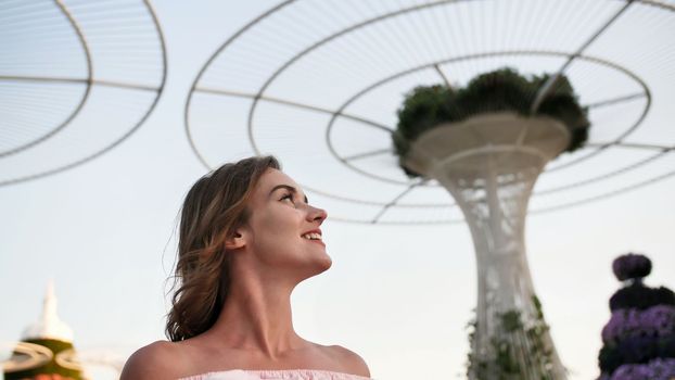 Girl on the background futuristic metal flowers in Dubai Miracle Garden Park