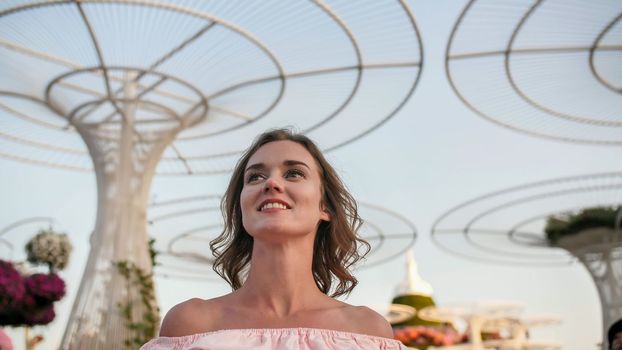 Girl on the background futuristic metal flowers in Dubai Miracle Garden Park