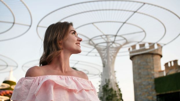 Girl on the background futuristic metal flowers in Dubai Miracle Garden Park