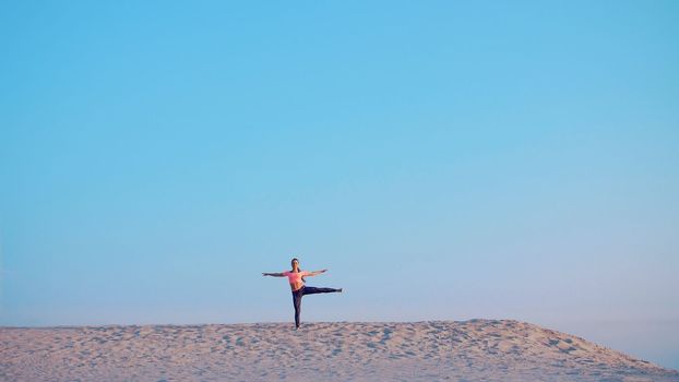 Healthy, young beautiful woman meditating, stretching, practicing yoga on the sea beach, at sunrise, Makes exercises for balance and coordination, deep muscle tone. High quality photo