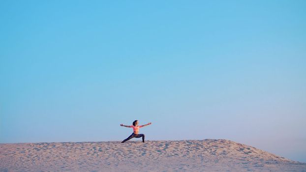 Healthy, young beautiful woman meditating, stretching, practicing yoga on the sea beach, at sunrise, Makes exercises for balance and coordination, deep muscle tone. High quality photo