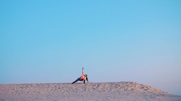 Healthy, young beautiful woman meditating, stretching, practicing yoga on the sea beach, at sunrise, Makes exercises for balance and coordination, deep muscle tone. High quality photo