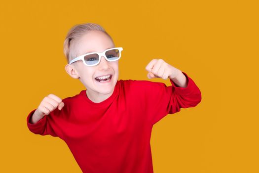 a child in children's 3D glasses joyfully raises his hands