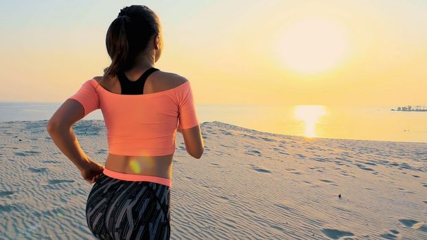 Healthy, young sports beautiful woman runs along the sand, on the beach, in summer, towards the sun, at the sunrise. High quality photo