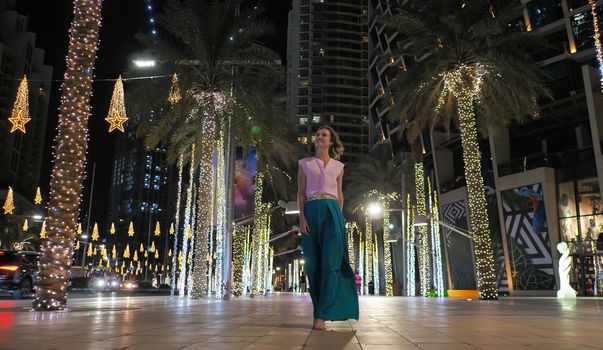 A young woman is walking along the evening Dubai