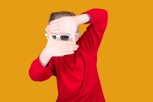 funny kid in 3D movie glasses holds his hands together and looks through them