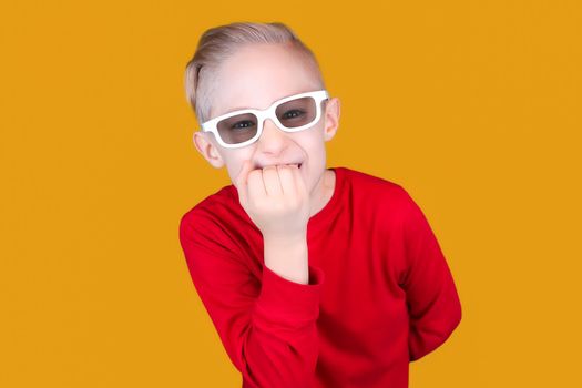 a child in children's 3D glasses bites his nails in surprise