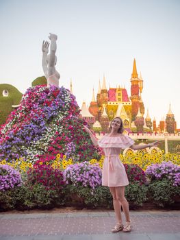 Girl posing on the background of the exposition of the statue of a ballerina. In the Garden of Miracles and Flowers in Dubai