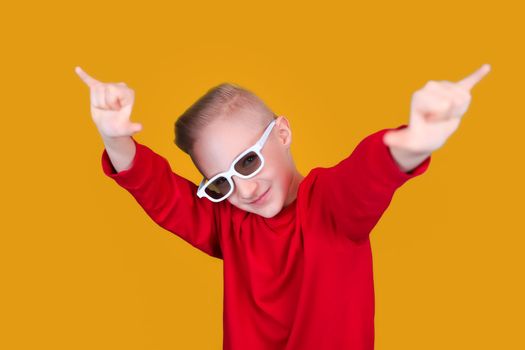 a cool and cheerful child in red clothes and glasses shows hand gestures on a yellow background