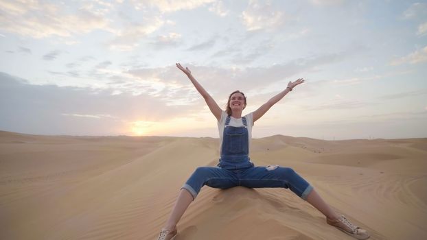 A happy girl in the desert of the Arab Emirates throws up sand