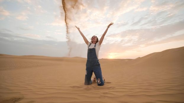 A happy girl in the desert of the Arab Emirates throws up sand