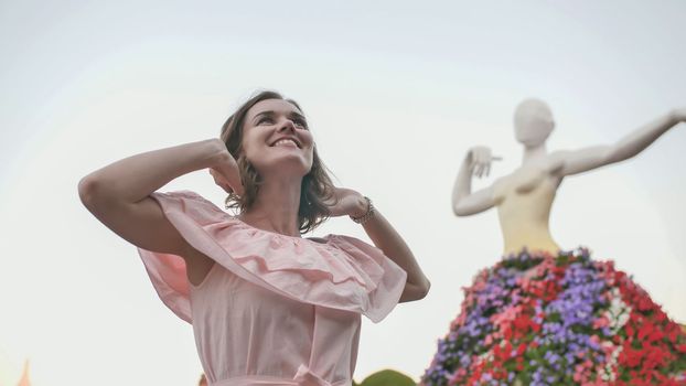 Girl posing on the background of the exposition of the statue of a ballerina. In the Garden of Miracles and Flowers in Dubai