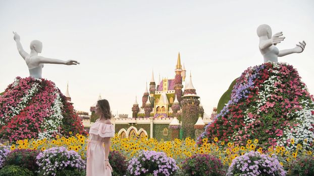 Girl posing on the background of the exposition of the statue of a ballerina. In the Garden of Miracles and Flowers in Dubai