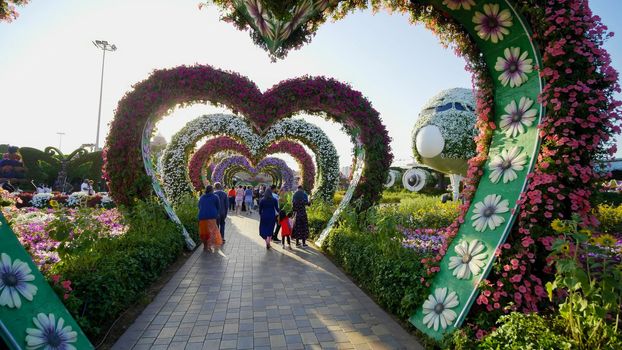 Heart shaped flower beds at the Alley of Hearts. Dubai Miracle Garden is famous for its extraordinary flower installations. A couple of people walking around at the park.