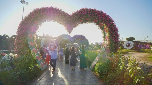 Heart shaped flower beds at the Alley of Hearts. Dubai Miracle Garden is famous for its extraordinary flower installations. A couple of people walking around at the park.