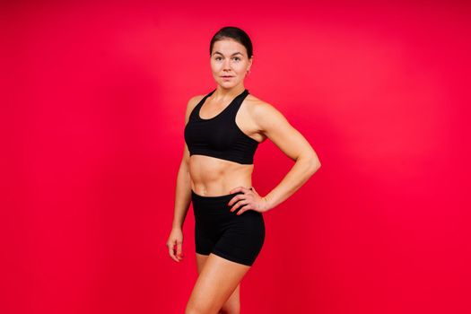 Strong sportswoman in boxing gloves prepared high kick. Isolated on a white, red, yellow background