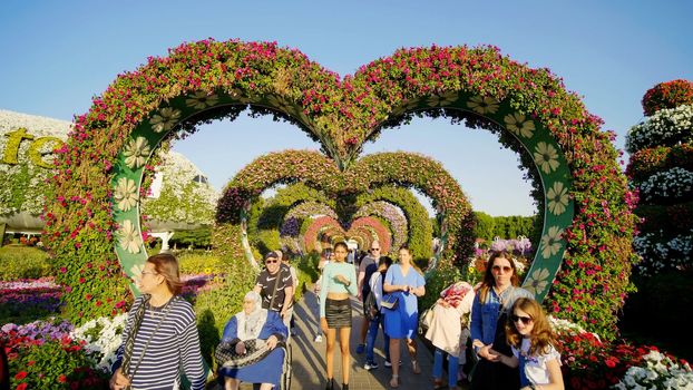 Heart shaped flower beds at the Alley of Hearts. Dubai Miracle Garden is famous for its extraordinary flower installations. A couple of people walking around at the park.