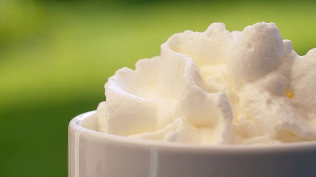Extreme close up putting whipping cream into a cup. Macro ready-made aerosol whipping cream. Fresh tasty food concept.