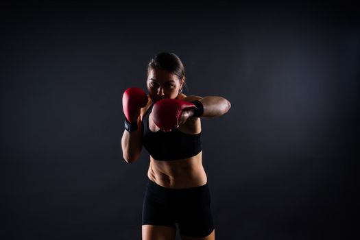 Strong sportswoman in boxing gloves prepared high kick. Isolated on a white, red, yellow background