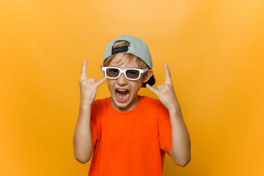a child in a cap and glasses for watching movies shows heavy metal gestures and shouts loudly