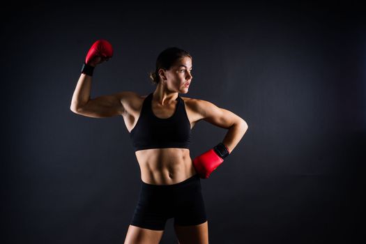 Strong sportswoman in boxing gloves prepared high kick. Isolated on a white, red, yellow background