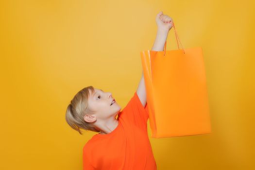 the boy held up an orange-colored paper shopping bag