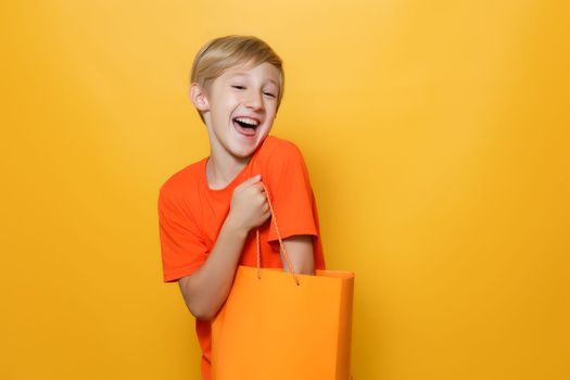 the boy has put his hand in an orange paper bag and is happy