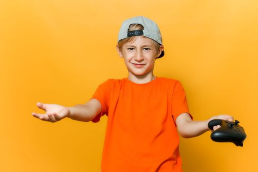 a boy in a cap and an orange T-shirt spread his hands in different directions he holds a gamepad in one hand