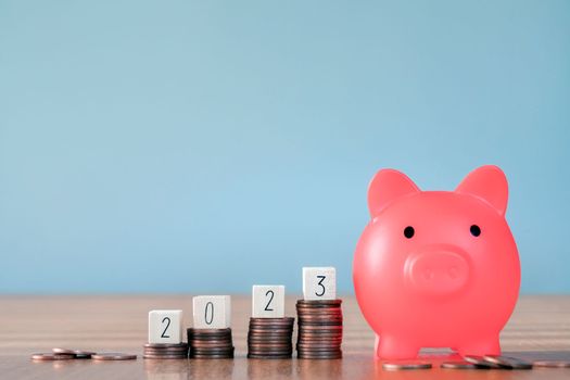 2023 on top stack of coins with gray background and copy space. saving money and financial plan concept for investment in new year 2023. pink piggy bank growth