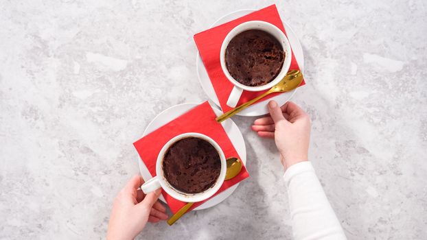 Flat lay. Step by step. Chocolate mug cakes garnished with whipped cream and chocolate hearts and lips.