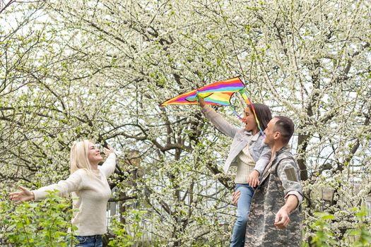 Soldier is meeting his family outdoors. Happy reunion of father and kids on the grass.