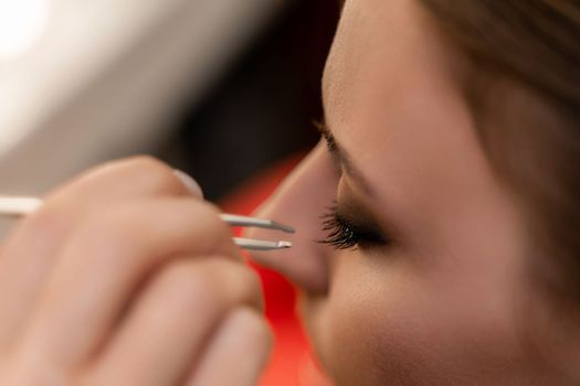 Makeup artist paints eyelashes to a woman in a beauty salon
