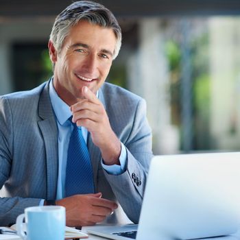 Smiling all the way to success. Cropped portrait of a handsome mature businessman looking confident while working on a laptop outdoors