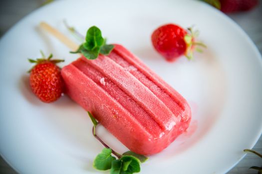 cooked homemade strawberry ice cream on a stick in a plate with strawberries