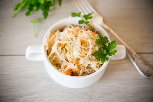 sauerkraut with carrots and spices in a bowl on a wooden table.