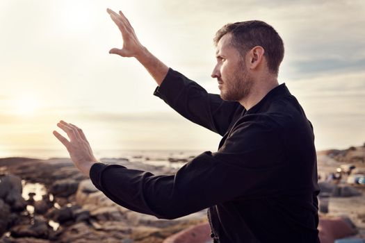 Tai chi, fitness and martial arts with man at beach for exercise and karate, self defense and zen with peace outdoor profile. Workout on rocks, energy balance and nature, wellness and calm sunrise