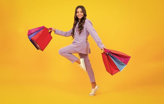 Stylish teen girl with shopping sale bags. Run and jump. Kid holding purchases