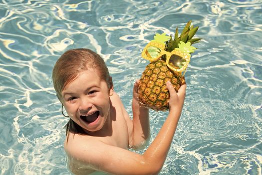 Child in swimming pool playing in summer water. Vacation and traveling with kids. Cute little boy swim on watter pool in the summer. Kids beach fun. Funny pineapple fruit for children