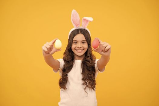 smiling kid in bunny ears hold eggs on yellow background, easter.